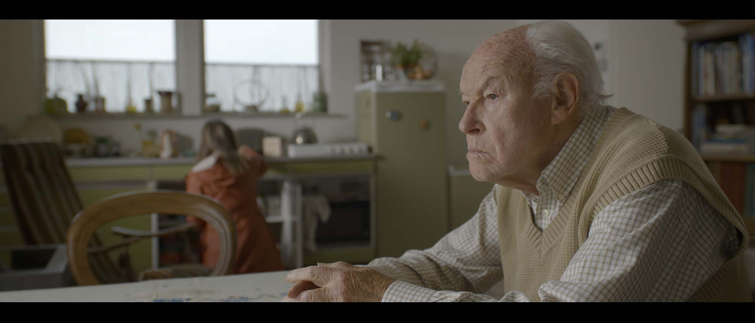 Alter grauhaariger Mann sitzt an einem Küchentisch