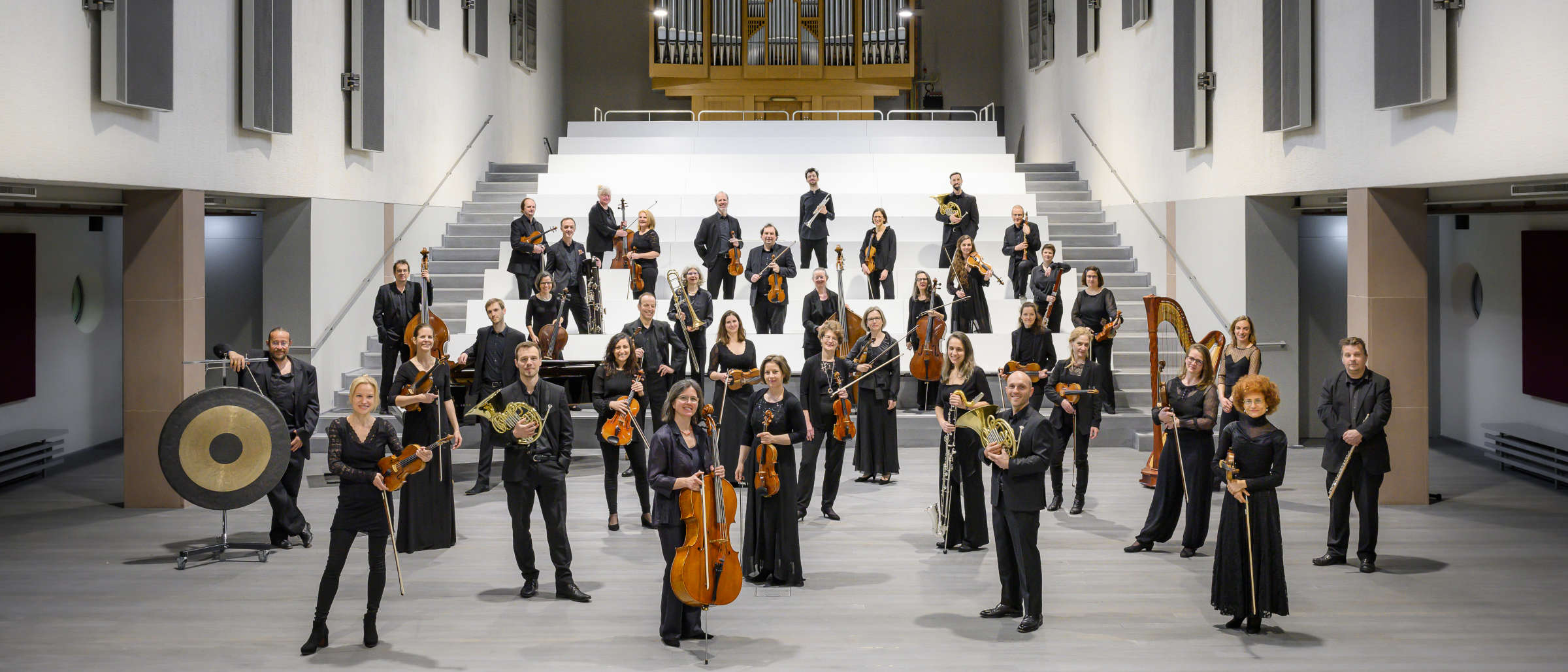 Mitglieder der Basel Sinfonietta stehen mit ihren Instrumenten vor einer Treppe